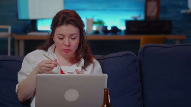 Γυναίκα που χρησιμοποιεί το lap-top για τις επιχειρήσεις και τρώει ασιατικό φαγητό — Αρχείο Βίντεο