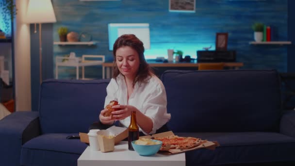 Fiatal nő eszik hamburgert és sült krumplit nevet — Stock videók