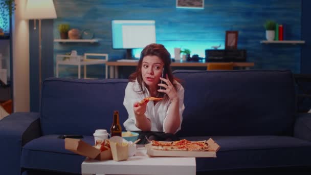Irriterad kvinna som pratar i telefon medan hon håller pizzabit — Stockvideo