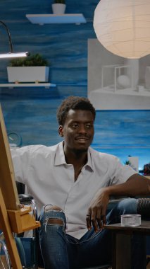 Tekerlekli sandalyede vazo çizen siyah bir adam.