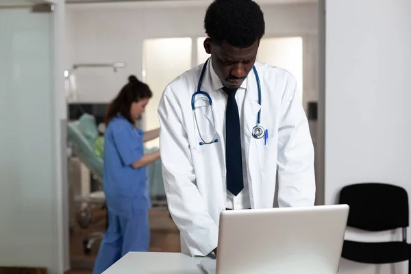 Портрет африканського лікаря, що стоїть за столом з ноутбуком — стокове фото