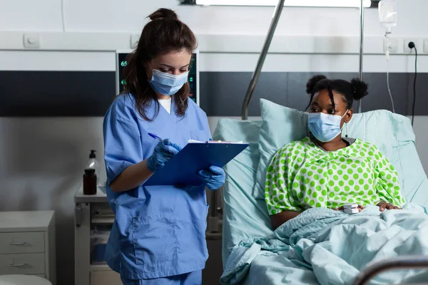 Blank verpleegster controleren op ziek Afrikaans amerikaanse patiënt — Stockfoto