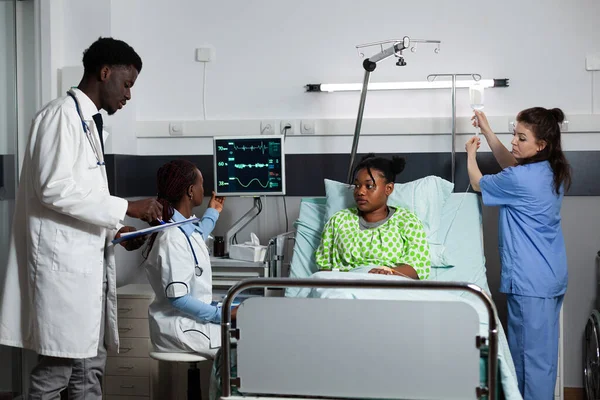 Çok ırklı tıp ekibi hastane koğuşundaki gençlere danışmanlık yapıyor. — Stok fotoğraf