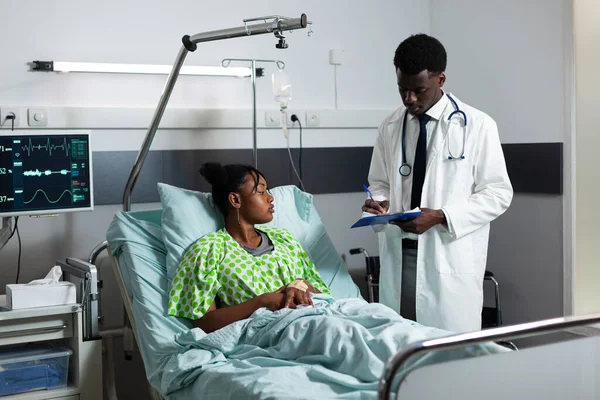 Médecin malade assis avec un jeune patient afro dans la salle d'hôpital — Photo