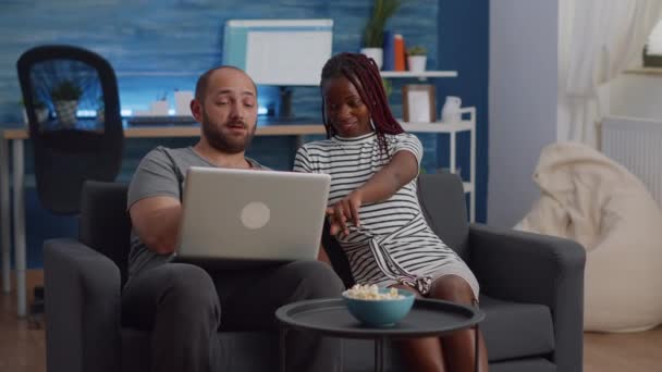 Young interracial couple looking at modern laptop — Stock Video