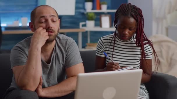 Jovem casal interracial pagando impostos com laptop na sala de estar — Vídeo de Stock