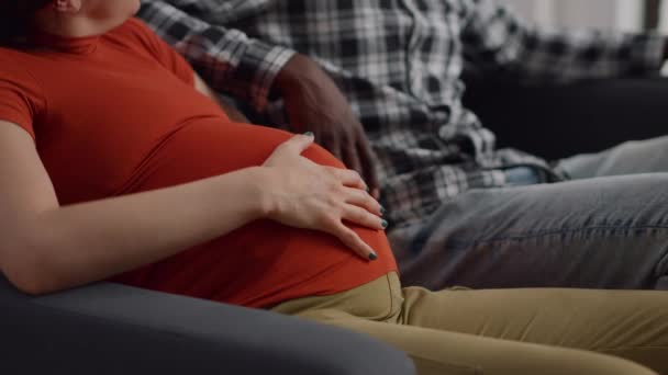 Primer plano de las manos interracial de la joven pareja en el vientre — Vídeo de stock