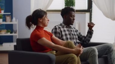 Oturma odasındaki kanepede kavga eden kızgın ırklar arası bir çift.