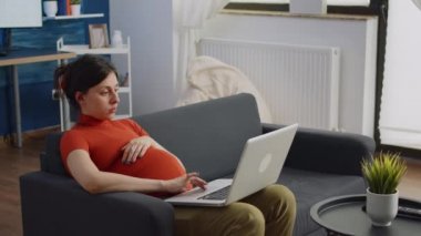 Hamileliği olan ırklar arası bir çift kanepede oturuyor.