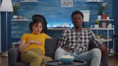 Hamilelik geçiren ve televizyon izleyen ırklar arası bir çift.