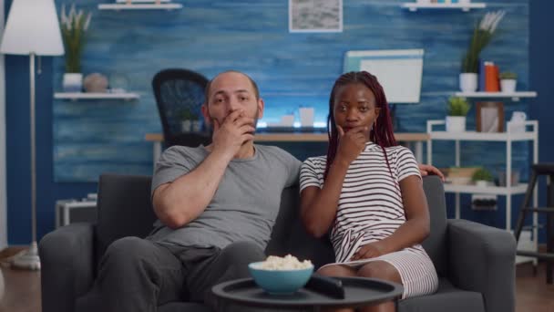ПОЛ межрасовой пары в шоке от просмотра телевизора — стоковое видео