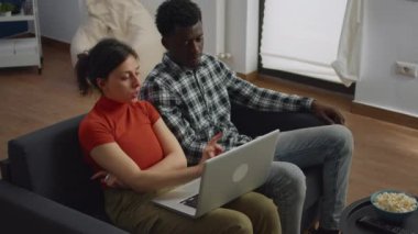 Dizüstü bilgisayara bakan iki ırklar arası evli çift.
