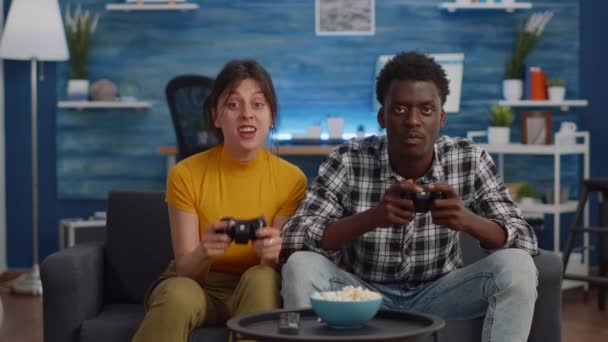 Couple interracial moderne jouant avec des joysticks pour le jeu vidéo — Video