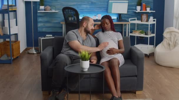Interraciaal paar verwachten kind en bonding op bank — Stockvideo
