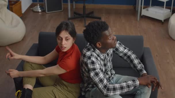 Joven pareja interracial luchando en el sofá en casa — Vídeos de Stock