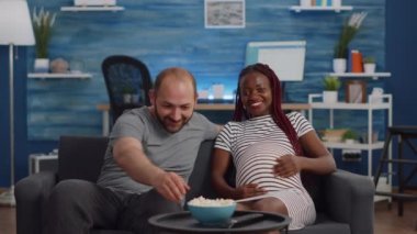 Hamilelik geçiren, televizyon izleyen ırklar arası bir çift.