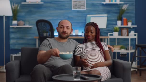 Międzyrasowy para z ciąży oglądanie filmu w telewizji — Wideo stockowe