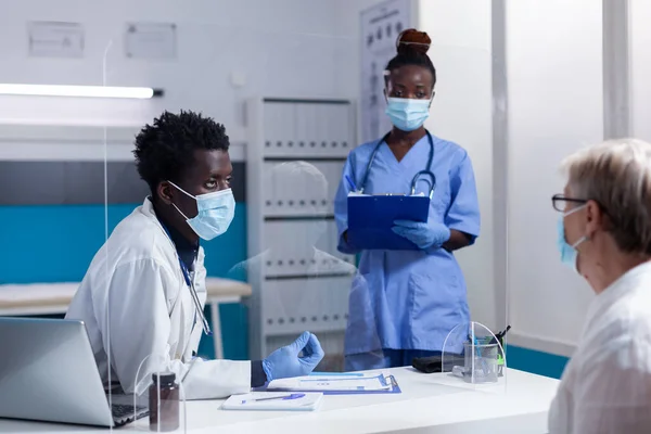 Afrikaans Amerikaans medisch team in gesprek met senior vrouw — Stockfoto