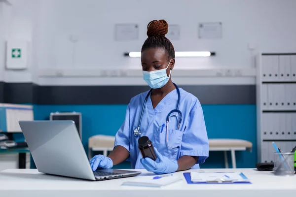 Portrait d'une infirmière afro-américaine tapant sur un clavier d'ordinateur portable — Photo