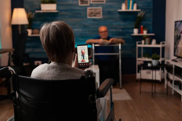 Donna sulla sedia a rotelle chiamando il medico utilizzando la videochiamata — Foto Stock