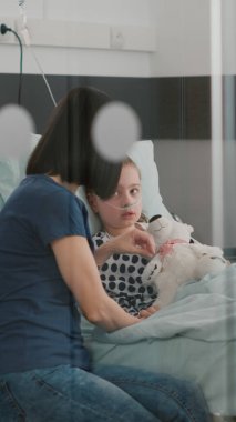 Hastane yatağında dinlenen hasta bir çocuk burun tüpü takıyor ve ameliyattan sonra iyileşiyor.