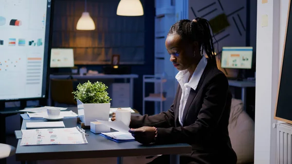 Femme d'affaires afro-américaine accro au travail analysant les statistiques marketing sur la paperasserie — Photo