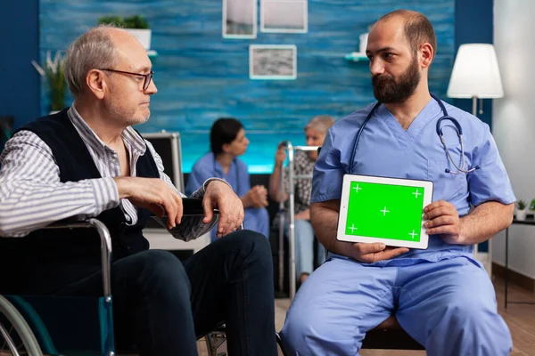 Asisstant vårdgivare hålla mock upp grön skärm kroma nyckel tablett med isolerad display — Stockfoto