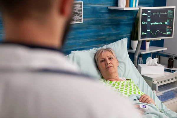 Gehandicapte gepensioneerde vrouw in bed bespreken medische behandeling met man assistent — Stockfoto