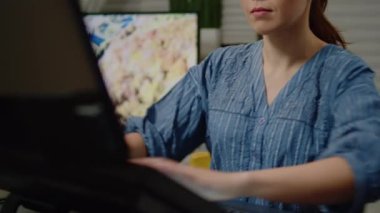 Stüdyoda bilgisayar ve monitör kullanan ressam