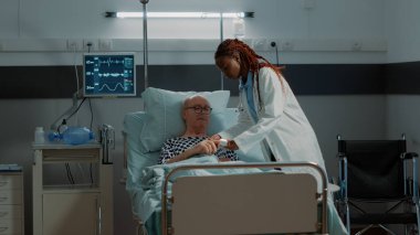 Hastane koğuşundaki hastanın eline oksimetre takan doktor.