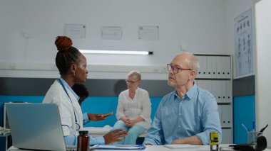 Kadın otolog yaşlı bir hastaya tıbbi muayene için danışmanlık yapıyor.