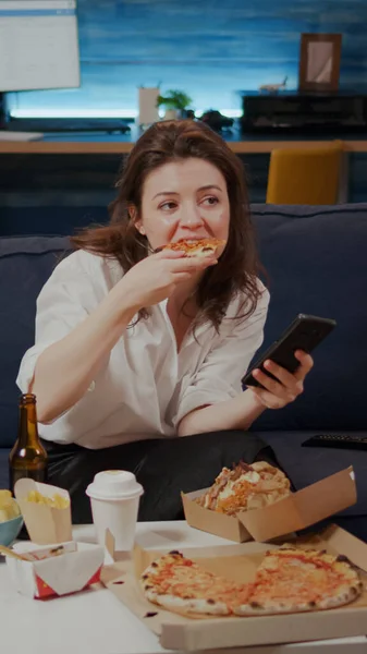 Zakenvrouw met smartphone tijdens het eten van plak pizza — Stockfoto