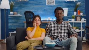 Genç ırklar arası televizyon izleyen ve patlamış mısır yiyen çift.