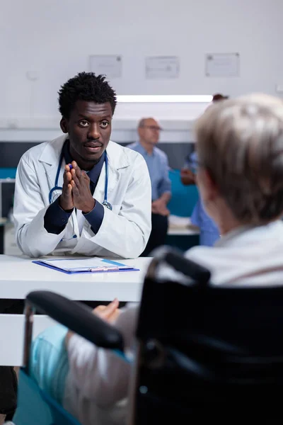 Jeune médecin noir parlant à un patient invalide au bureau — Photo