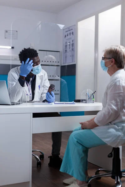 Sanitäter afrikanisch-amerikanischer Herkunft im Gespräch mit alten Patienten — Stockfoto