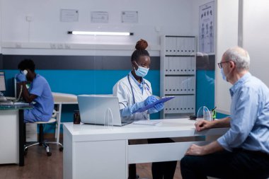 Doktorluk mesleği olan siyahi bir kadın yaşlı bir hastaya yardım ediyor