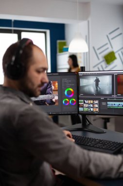 Kulaklıklı video yapımcısı iki ekranlı görüntü ve sesle çalışıyor