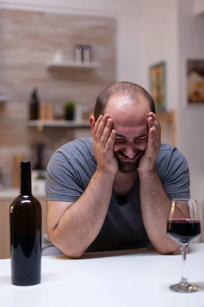 Depresyjny człowiek z alkoholizmem siedzący z butelką i kieliszkiem wina — Zdjęcie stockowe