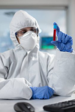 19. kovid19 'a karşı koruyucu giysili kimyager tıbbi boşaltıcıyı tutuyor.
