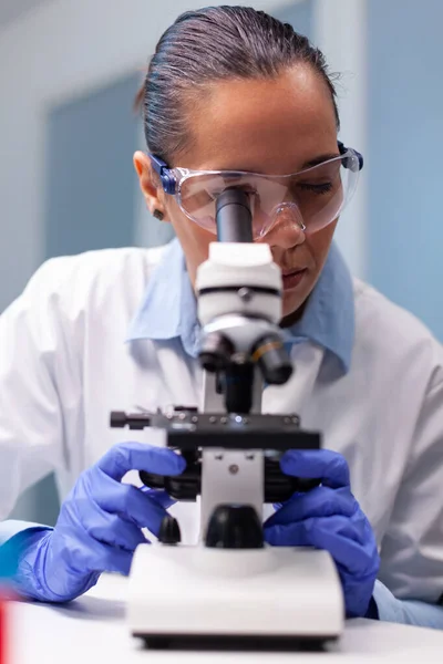 Científica doctora mirando la prueba genética del coronavirus usando microscopio médico —  Fotos de Stock