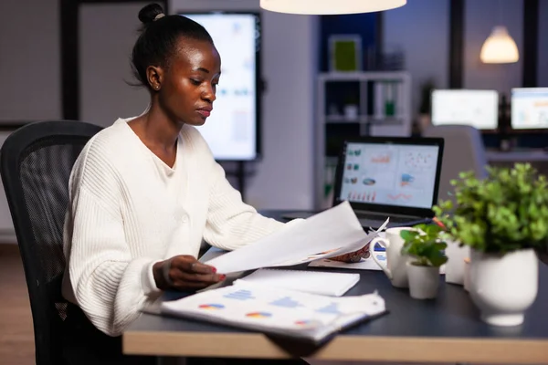 Femme d'affaires afro-américaine fatiguée focalisée regardant les rapports annuels de l'entreprise — Photo