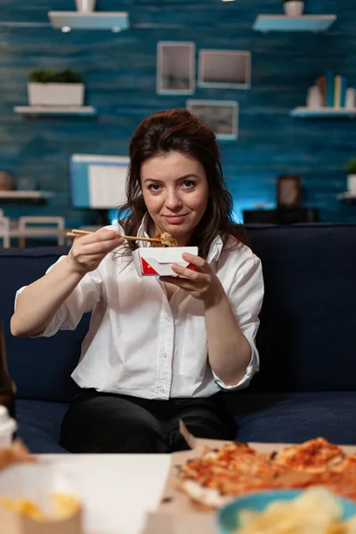 Portret van een blanke vrouw die in de camera kijkt en Chinese noedels eet — Stockfoto