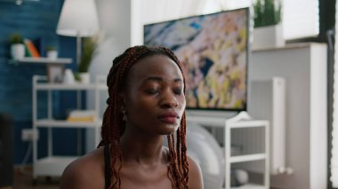 Nilüfer pozisyonunda meditasyon yapan, yoga minderinde oturan atletli kadının yakın çekimi.