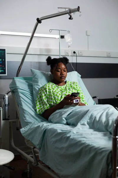 Jong Afrikaans amerikaanse volwassene zitten in ziekenhuis afdeling bed — Stockfoto