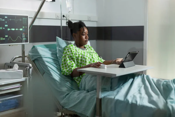 Jovem afro-americana usando tablet em cama de hospital — Fotografia de Stock