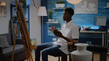 Sanat atölyesinde dijital tablet kullanan Afrikalı Amerikalı sanatçı