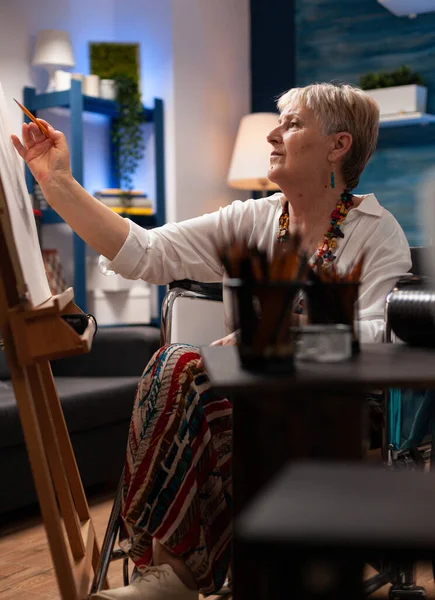 Vieja mujer inválida dibujando sobre lienzo usando lápiz — Foto de Stock