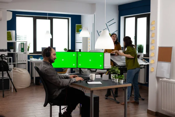 Umělec video tvůrce se sluchátky pomocí duálního monitoru nastavení se zelenou obrazovkou — Stock fotografie