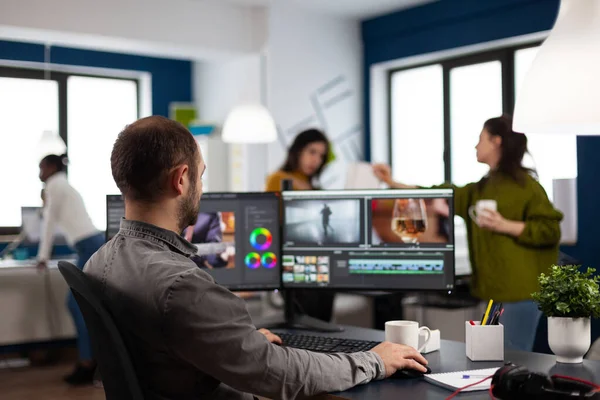 Editor de vídeo cortando imágenes trabajando en montaje de edición de películas en el ordenador con configuración de monitores duales — Foto de Stock