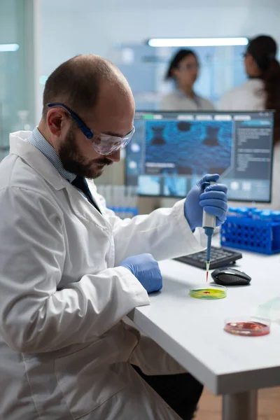 Scientist biologist man putting chemical fluid in petri dish using medical micropippete — Stock Photo, Image